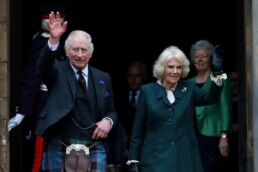 King Charles and Queen Camilla waving to a crowd